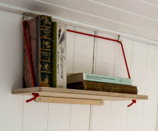 Everything Goes - Hang Shelf - storing books on a sloped boat wall. Birch ply with red rope.